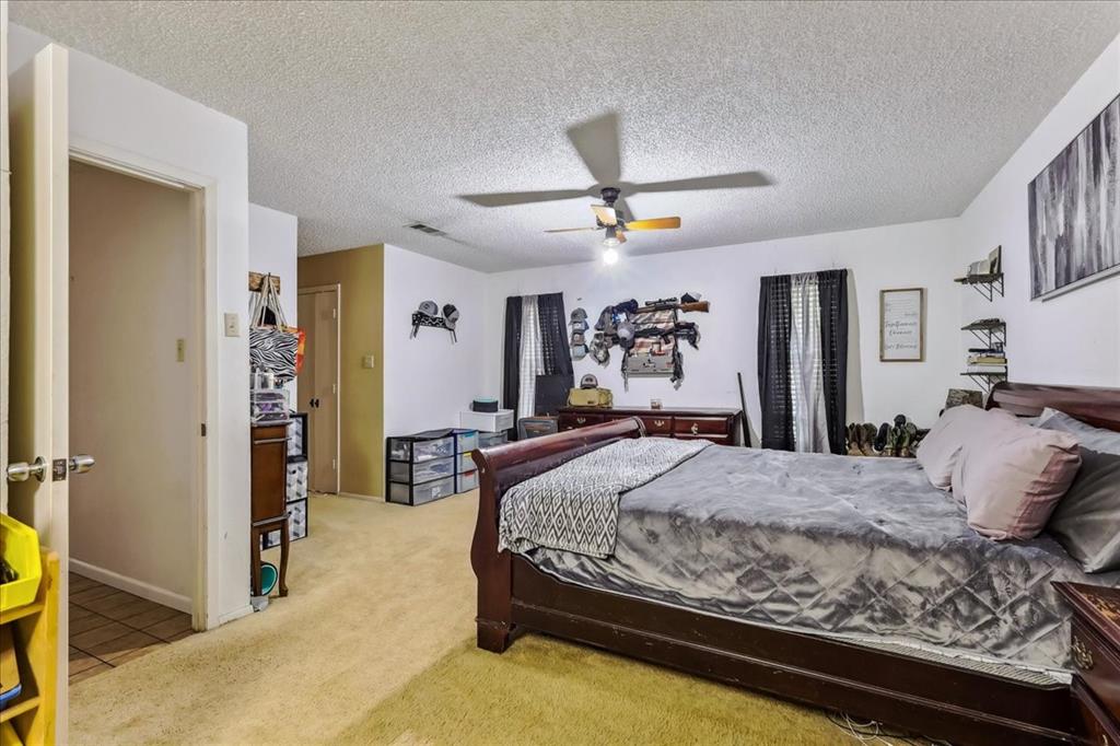 8123 Hilltop Road Argyle, TX 76226 - Photo 23 of 34 a bedroom with a large bed and a chandelier