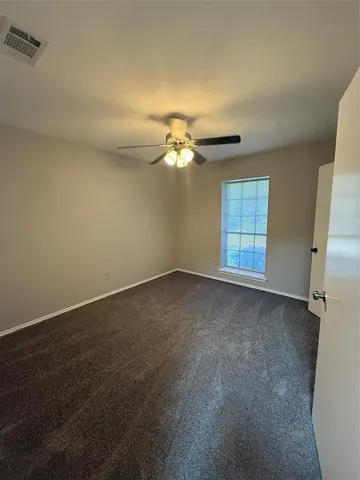an empty room with windows and fan