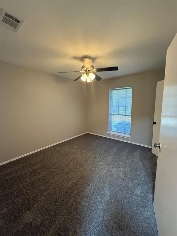 304 East Hickory Street, Unit A Kaufman, TX 75142 - Photo 11 of 12 an empty room with windows and fan
