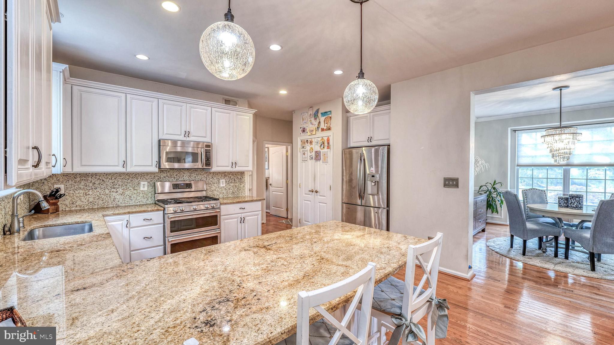 107 Millstone Way Monroeville, NJ 08343 - Photo 17 of 40 a large kitchen with stainless steel appliances granite countertop a stove a refrigerator a oven a sink a dining table and chairs with wooden floor