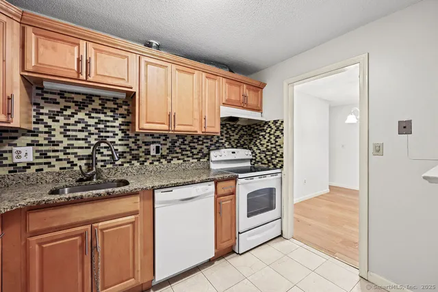 a kitchen with granite countertop a sink stove and cabinets