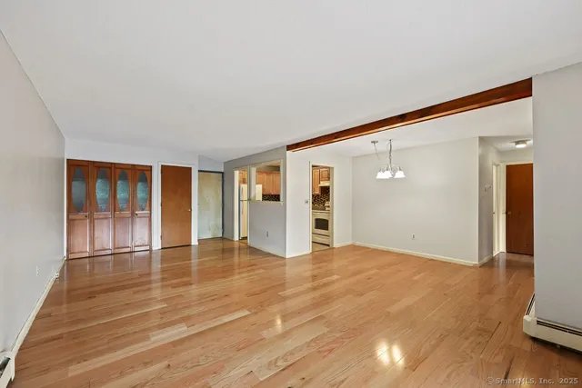 a view of an empty room with window and wooden floor