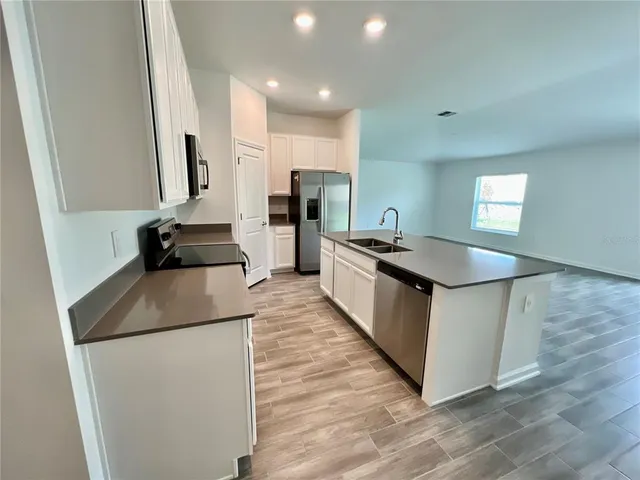 a kitchen with stainless steel appliances granite countertop a sink a stove a refrigerator a washer dryer and white cabinets