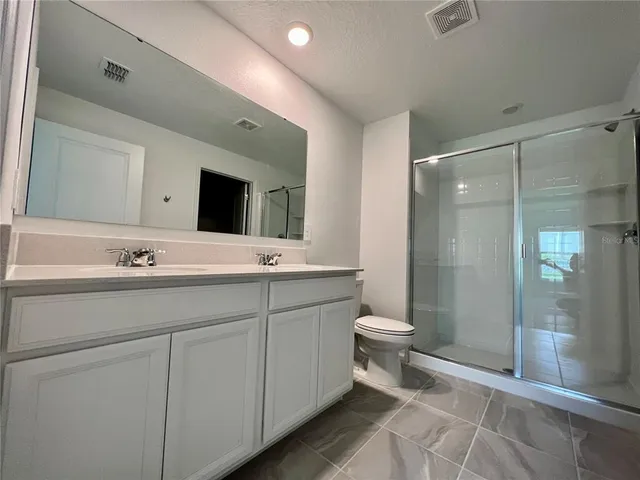 a bathroom with a double vanity sink toilet and shower