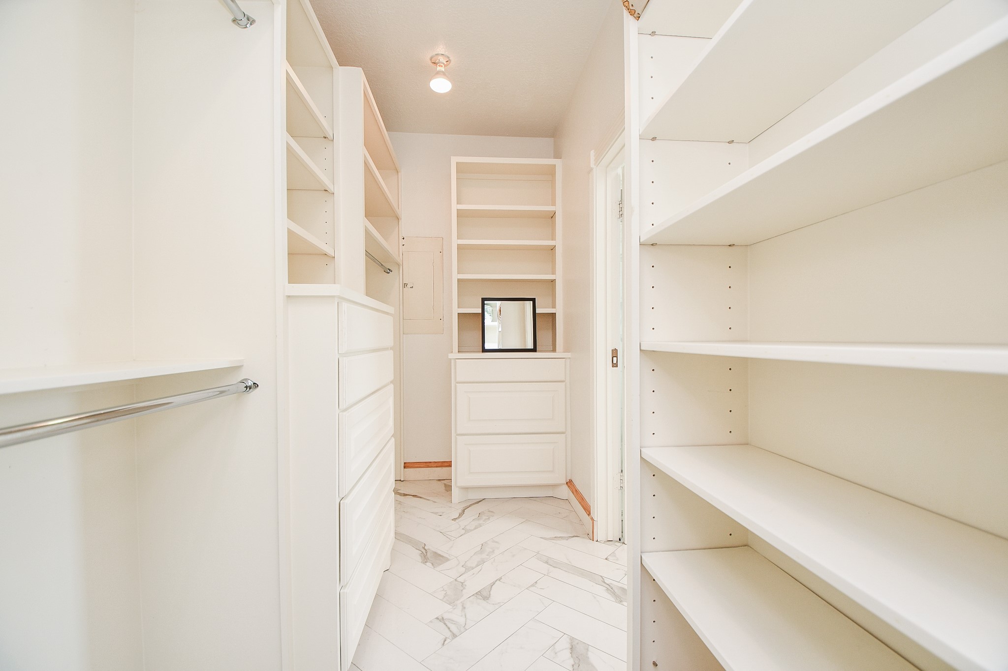 263 Wood Loop Street Houston, TX 77015 - Photo 30 of 45 This photo shows a spacious, bright walk-in closet with white shelving and cabinetry, offering ample storage. The floor features elegant light-colored tiles, and there's overhead lighting to enhance visibility.