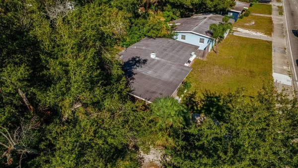 an aerial view of residential house with outdoor space and trees all around