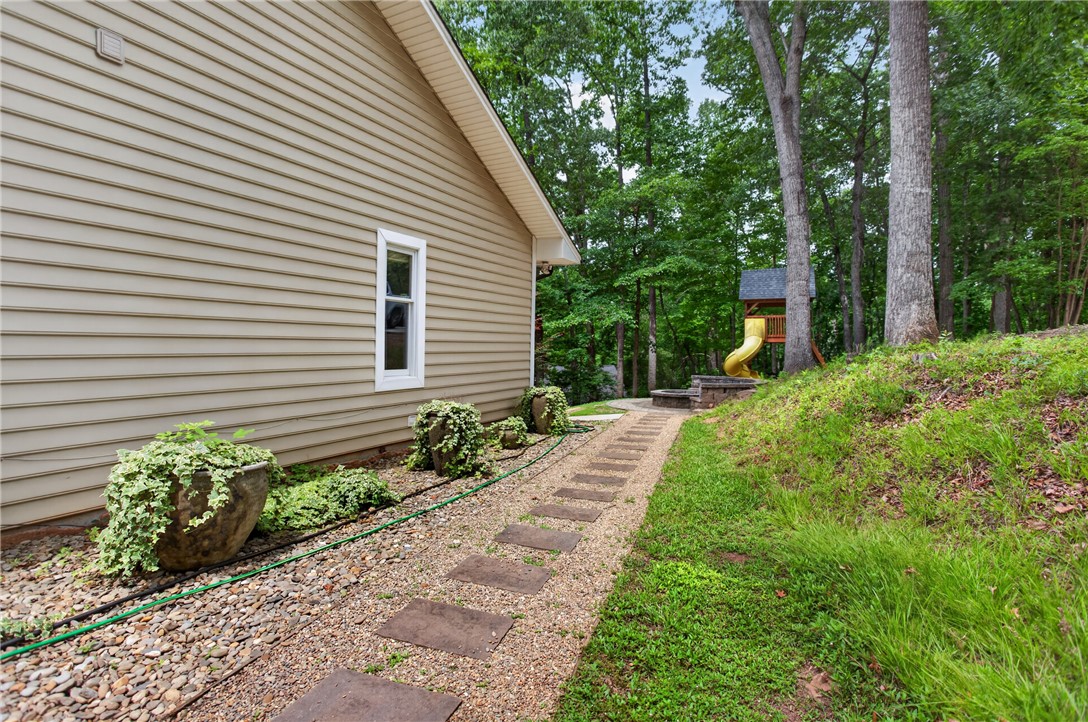 136 Loran Pointe Circle Seneca, SC 29672 - Photo 41 of 50 A quaint pathway leads to a delightful playhouse nestled among towering trees, offering a private, wooded escape.