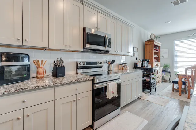 a kitchen with stainless steel appliances granite countertop a sink a stove and cabinets