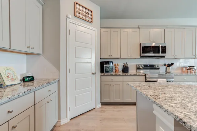 a kitchen with granite countertop white cabinets and stainless steel appliances