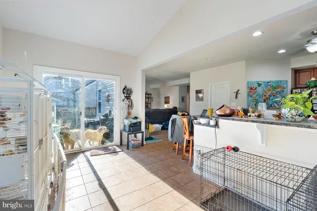 a living room with stainless steel appliances furniture a rug and a kitchen view