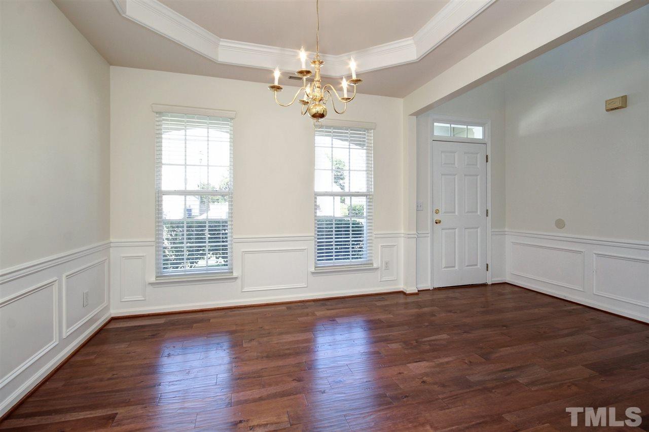 7444 Lagrange Drive Raleigh, NC 27613 - Photo 4 of 30 an empty room with wooden floor chandelier and windows