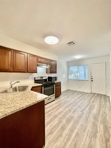 a kitchen with stainless steel appliances granite countertop a stove a sink and a microwave