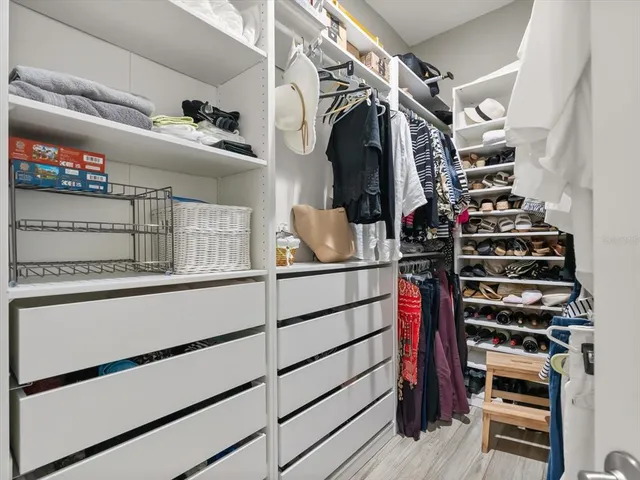 a view of walk in closet with clothes and shoes