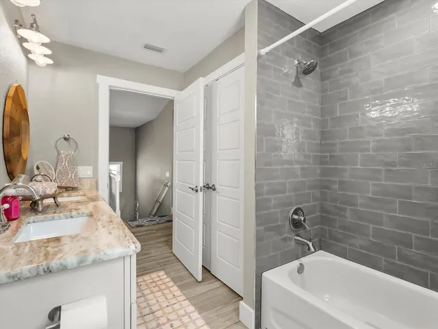 a bathroom with a granite countertop sink a mirror and a bathtub