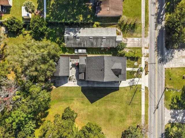 an aerial view of a house with swimming pool and large trees