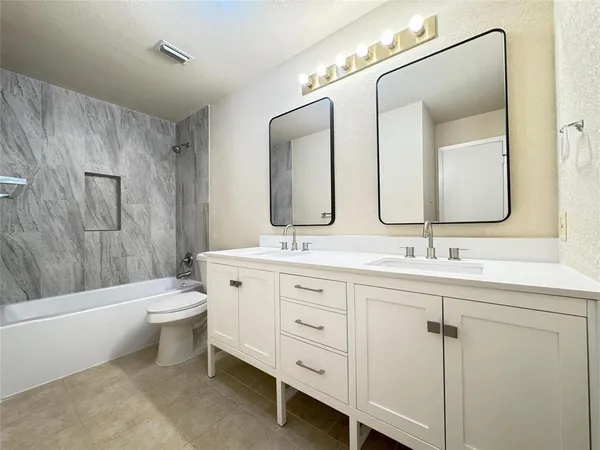 a bathroom with a double vanity sink toilet mirror and bathtub