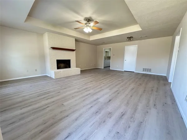 a view of an empty room with wooden floor and a fireplace