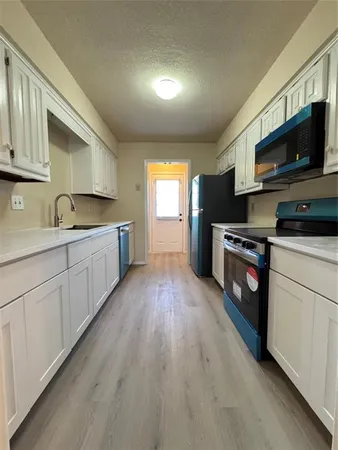 a kitchen with stainless steel appliances granite countertop a sink and cabinets with wooden floor