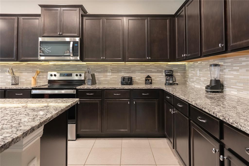 4425 Kaipo Road Davenport, FL 33897 - Photo 13 of 100 a kitchen with granite countertop a sink dishwasher stove and cabinets with wooden floor