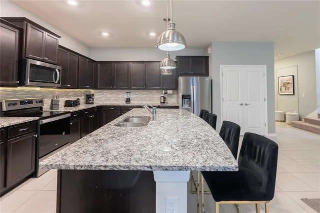 a kitchen with stainless steel appliances granite countertop a sink a stove and a wooden cabinets