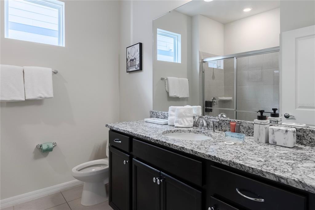 4425 Kaipo Road Davenport, FL 33897 - Photo 4 of 100 a bathroom with a granite countertop sink a toilet and a mirror