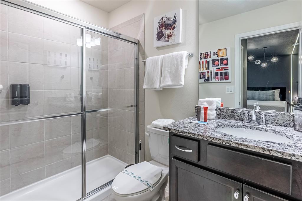 4425 Kaipo Road Davenport, FL 33897 - Photo 57 of 100 a bathroom with a granite countertop sink a toilet and shower