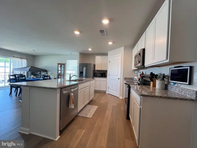 a large kitchen with stainless steel appliances granite countertop a lot of counter space and wooden floors