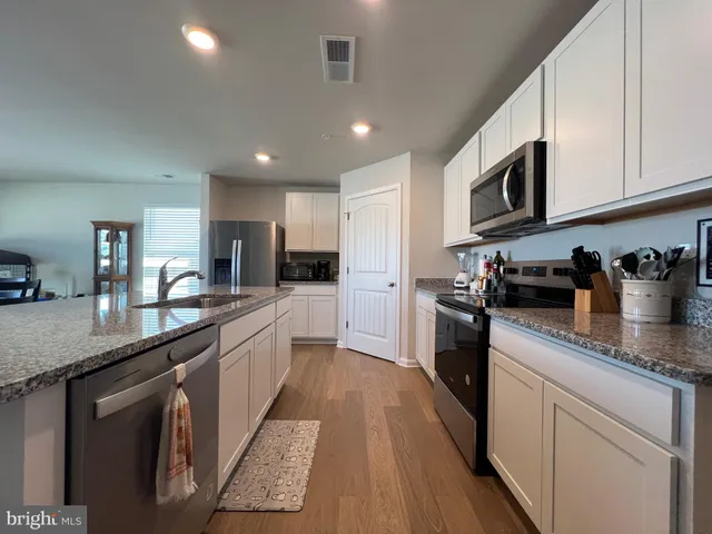 a large kitchen with stainless steel appliances granite countertop a lot of counter space and a sink