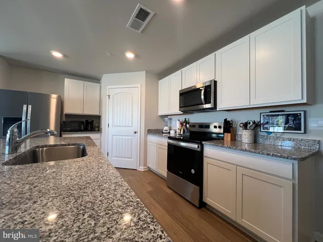 a kitchen with granite countertop a sink and steel appliances
