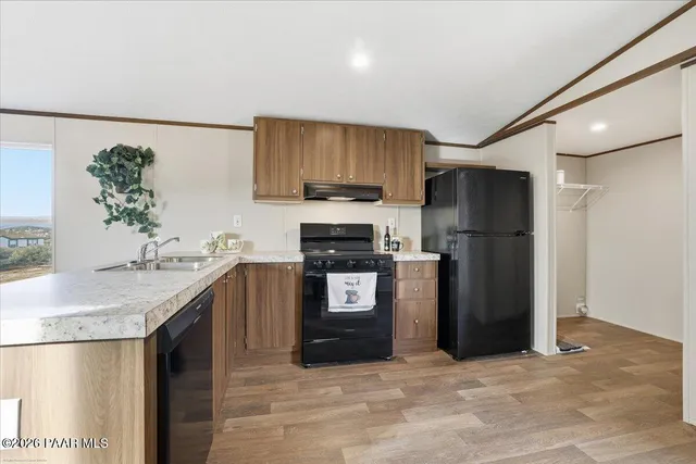 a kitchen with stainless steel appliances granite countertop a refrigerator a stove and a sink with wooden floor