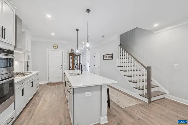 a large kitchen with cabinets chairs and wooden floor