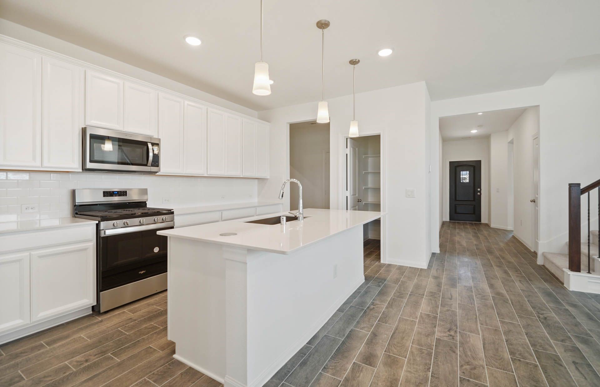 16193 Sepia Manor Street Conroe, TX 77302 - Photo 3 of 19 a kitchen with stainless steel appliances a stove top oven a sink a refrigerator white cabinets and wooden floor