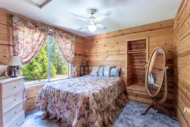 a bedroom with a bed a chandelier and a large window with the outer view