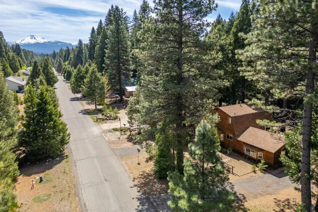 an aerial view of a house with a yard and trees all around