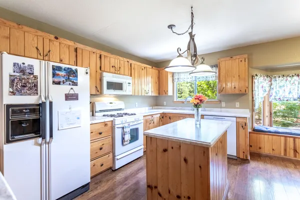 a kitchen with granite countertop a sink appliances cabinets and a large window
