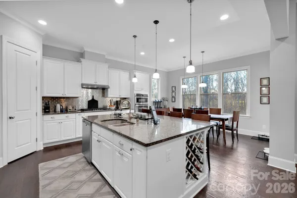 a kitchen with refrigerator a stove a center island a dining table and chairs