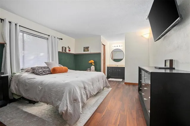 a bedroom with a bed and a flat tv screen on dresser