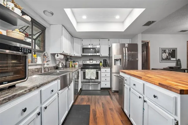 a kitchen with stainless steel appliances granite countertop a lot of counter space cabinets and wooden floor