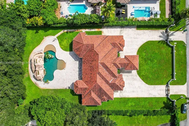 an aerial view of a house with swimming pool and outdoor seating