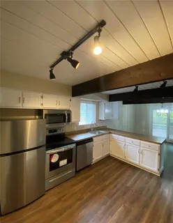 a kitchen with granite countertop a refrigerator and a stove top oven