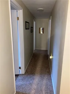 a view of a hallway with wooden floor and a bathroom