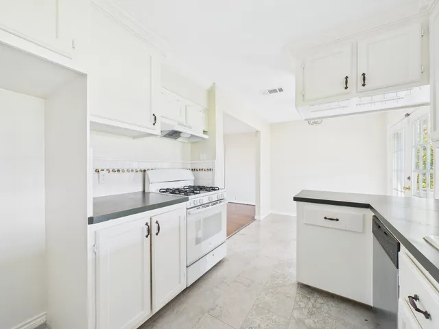 a kitchen with granite countertop white cabinets and white appliances