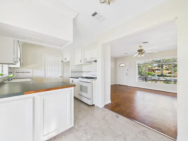 a kitchen with stainless steel appliances granite countertop a refrigerator a sink a stove top oven a large window with white walls