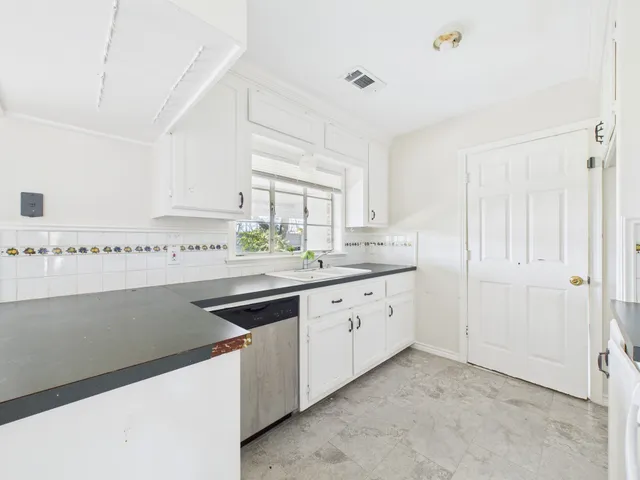a kitchen with white cabinets and appliances