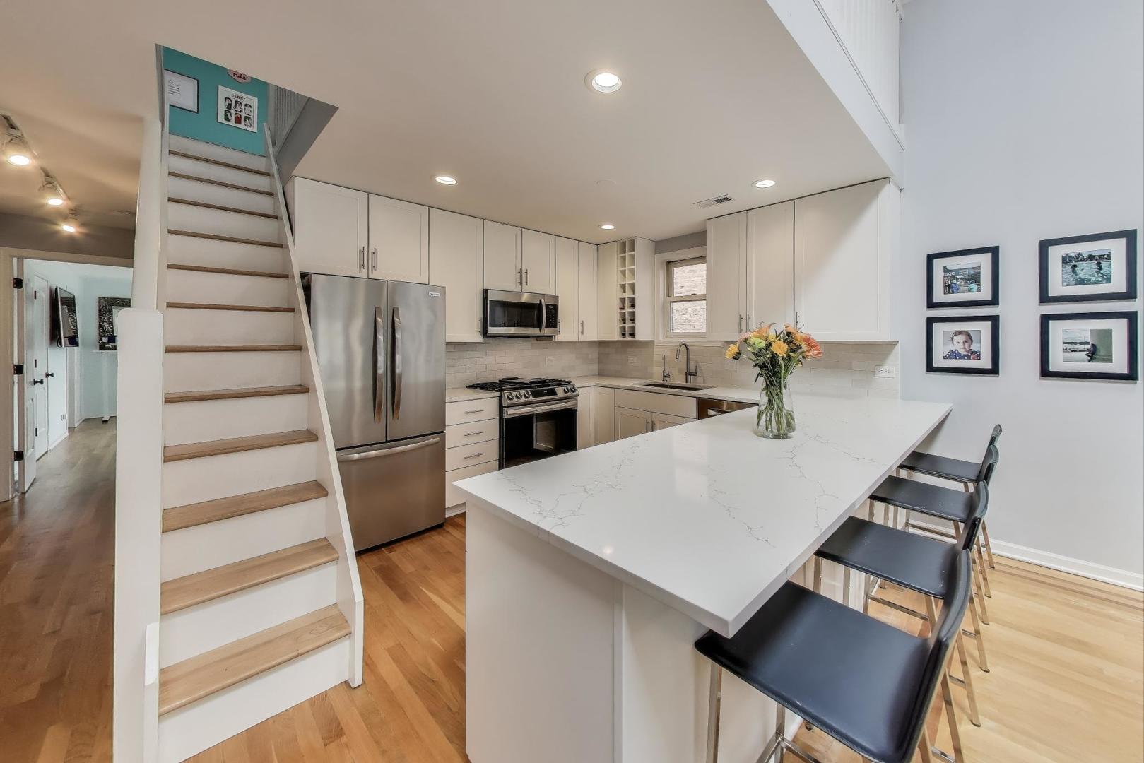 1862 North Halsted Street, Unit 3N Chicago, IL 60614 - Photo 9 of 25 a kitchen with stainless steel appliances a refrigerator a stove a sink dishwasher and white cabinets with wooden floor