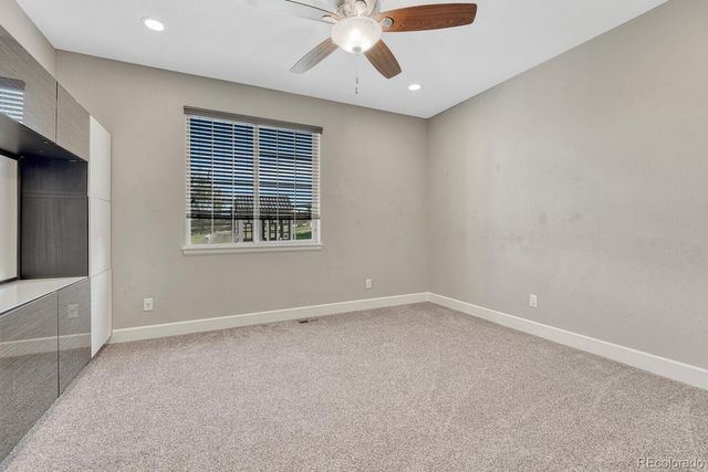 an empty room with chandelier fan and windows