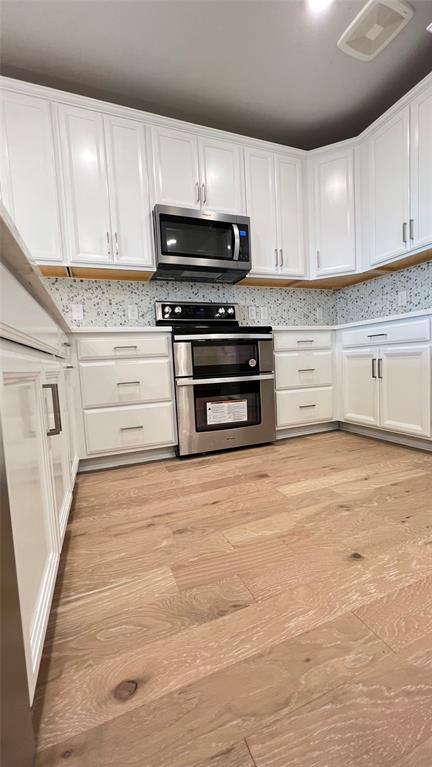 651 Watters Road, Unit 3300 Allen, TX 75013 - Photo 11 of 25 Kitchen featuring light wood-type flooring, appliances with stainless steel finishes, and white cabinetry