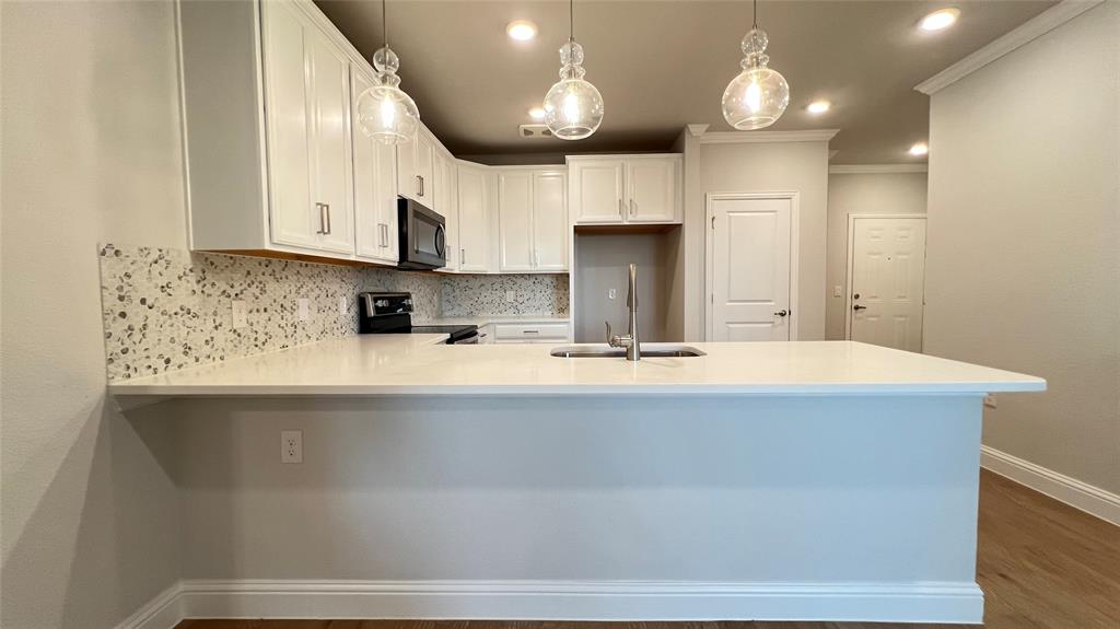 651 Watters Road, Unit 3300 Allen, TX 75013 - Photo 12 of 25 Kitchen with dark hardwood / wood-style flooring, backsplash, stainless steel appliances, sink, and kitchen peninsula