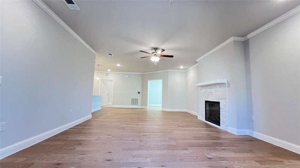 651 Watters Road, Unit 3300 Allen, TX 75013 - Photo 8 of 25 Unfurnished living room featuring light wood-type flooring, ornamental molding, a fireplace, and ceiling fan