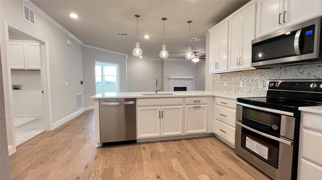 651 Watters Road, Unit 3300 Allen, TX 75013 - Photo 9 of 25 Kitchen featuring pendant lighting, stainless steel appliances, kitchen peninsula, white cabinetry, and light wood-type flooring